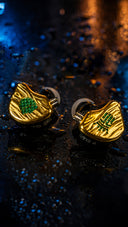 Tipsy TG4 gold and black in-ear monitors on a wet reflective surface